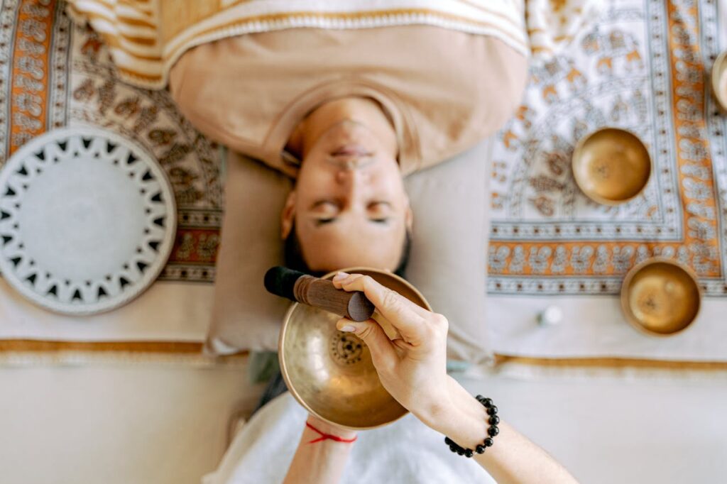 A man experiencing deep relaxation during a sound therapy session with Tibetan singing bowls for holistic wellness.