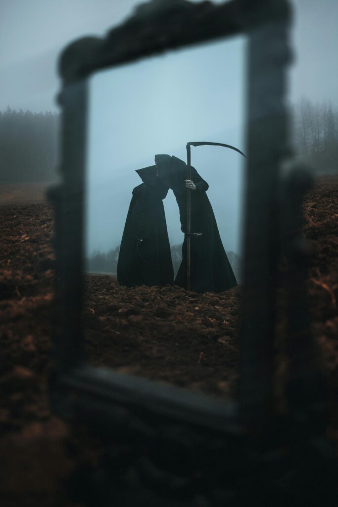 Eerie figure with a scythe, reflected in a mirror on a foggy landscape.