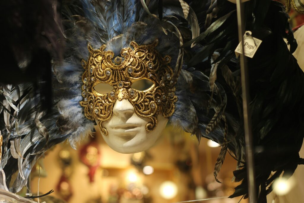 Ornate Venetian mask with golden details and blue feathers, embodying Italian tradition.